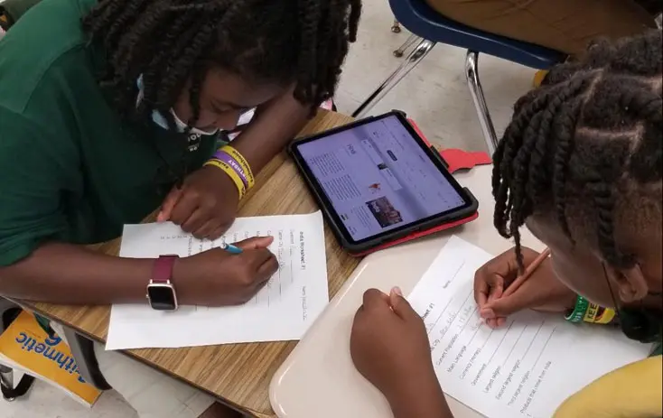 Two students work on their homework at a table.