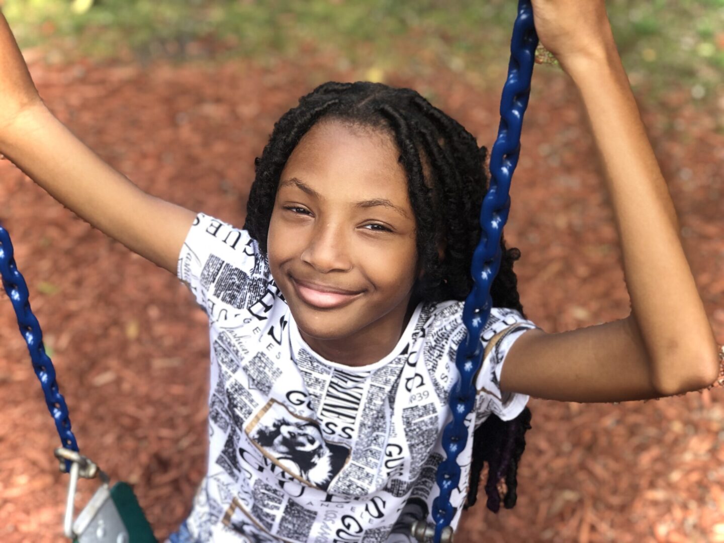 A young girl with long hair is swinging on a swing.