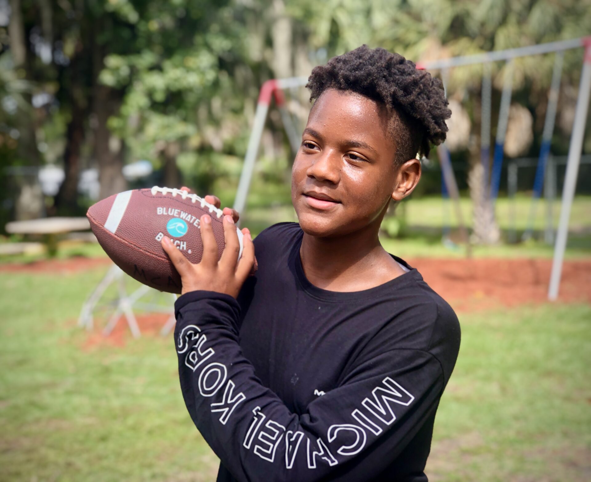 A young man holding a football in his hands.