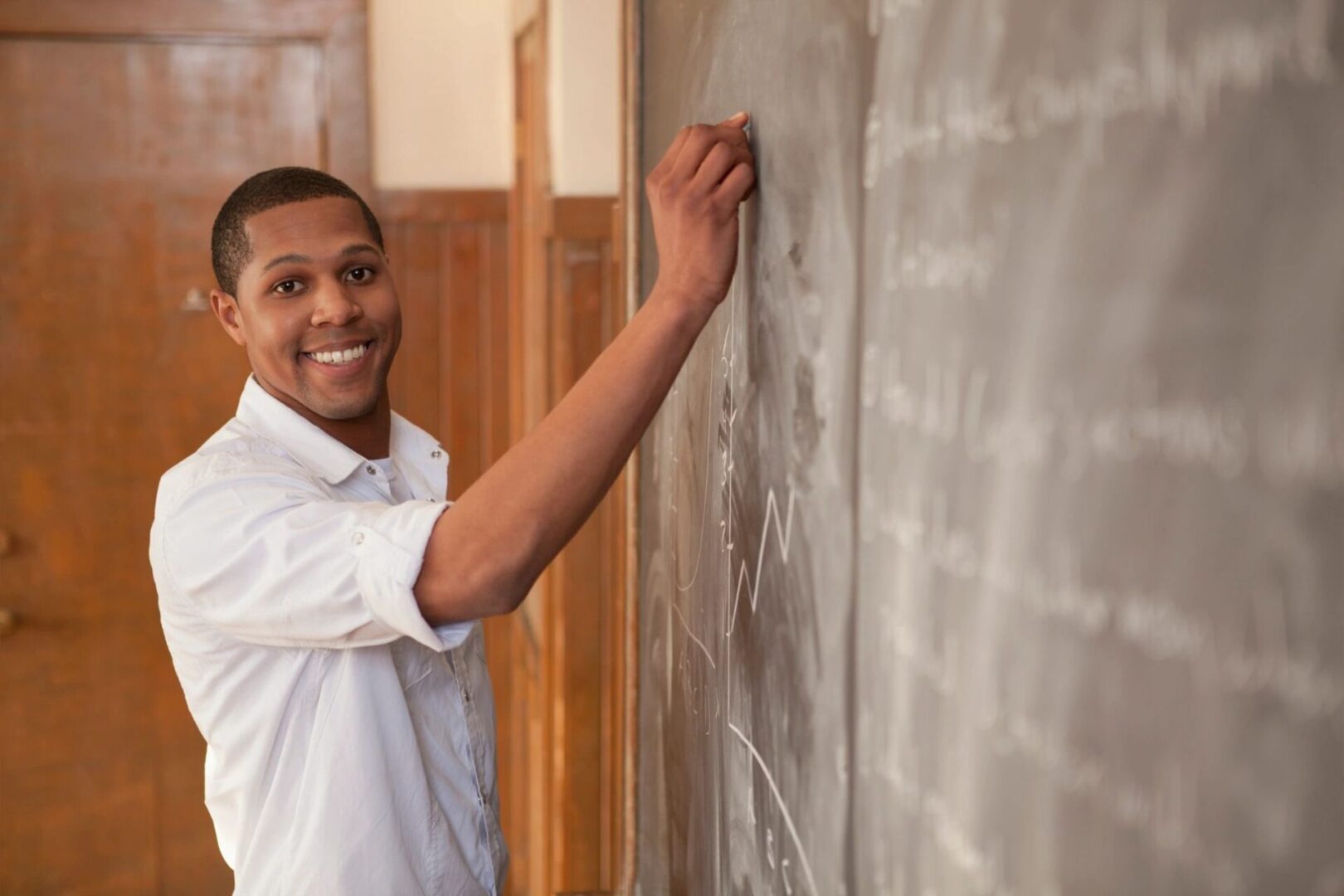 A man is smiling while writing on the wall.